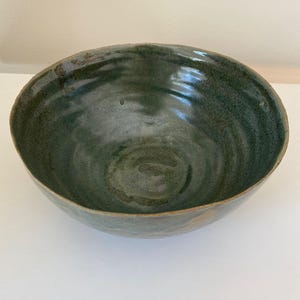 May include: A large, green ceramic bowl with a swirling pattern. The bowl has a wide rim and a deep, rounded interior.