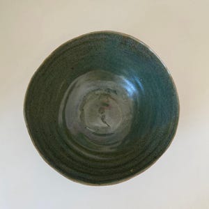 May include: A green ceramic bowl with a textured, swirling design. The bowl is glazed and has a slightly iridescent finish.