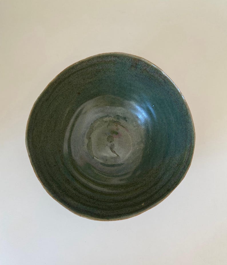 May include: A green ceramic bowl with a textured, swirling design. The bowl is glazed and has a slightly iridescent finish.