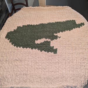 May include: A large, cream-colored knitted throw blanket with a green outline of the state of Tennessee.