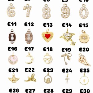 May include: A selection of gold-coloured charms, each with a unique design. Charms include numbers, a football, a heart, a planet, an eye, a moon, a bow, angels, a cross, a clover, and a "Good Luck" tag. The charms are labelled E1 to E30.