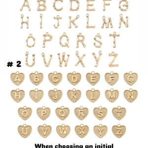 May include: Gold-coloured alphabet charms in two styles. The first style features individual letters, while the second features letters within heart-shaped frames. Text on the image instructs how to select an initial.