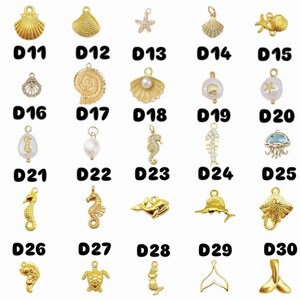May include: A selection of gold-coloured charms featuring marine life designs. The charms include starfish, seashells, seahorses, and other sea creatures. Each charm is labelled with a number from D1 to D35.