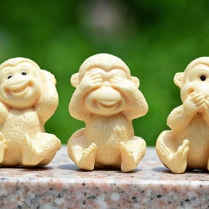 以下が含まれることがあります： クリーム色の小さな猿の置物が3体、一列に並んでいます。1体目の猿は両手で耳を塞ぎ、2体目の猿は両手で目を覆い、3体目の猿は両手で口を覆っています。それぞれの置物は滑らかな質感で、均一なクリーム色をしています。