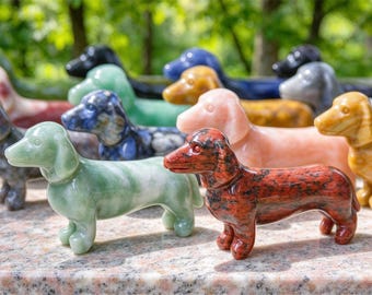 May include: A collection of small, hand-carved stone dachshund figurines in various colors, including light green, red speckled, pink, yellow, blue, and black. Each smooth, polished sculpture depicts the dog in a standing position.