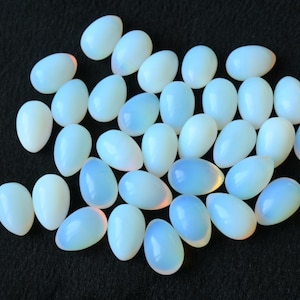 May include: A collection of smooth, oval-shaped, white opal stones with iridescent rainbow colors.