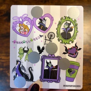 K&ouml;nnte beinhalten: Eine quadratische Karte mit gestreiftem Hintergrund mit verschiedenen Illustrationen eines Disney-B&ouml;sewichts, darunter ein Portr&auml;t, ein Drache und ein Kaffeebecher. Die Karte enth&auml;lt den Text "BOW TO ME!" und mehrere Rubbelkreise. Die Karte ist mit "DESIGNSBYSOL2024" beschriftet.