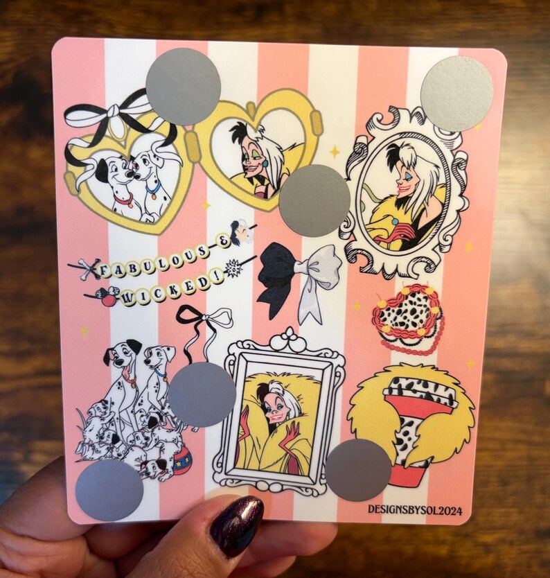 K&ouml;nnte beinhalten: Eine rosa-wei&szlig; gestreifte Karte mit Illustrationen von Cruella de Vil und Dalmatinerhunden. Die Karte enth&auml;lt den Text "Fabulous & Wicked" und mehrere Rubbelkreise. Das Design beinhaltet Schleifen, Herzen und gerahmte Portr&auml;ts.