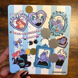 K&ouml;nnte beinhalten: Ein rechteckiges Stickerbogen mit hellblau-wei&szlig; gestreiftem Hintergrund. Das Bogen zeigt Illustrationen von Charakteren aus Arielle, die Meerjungfrau, darunter Arielle und Ursula. Der Text "POOR-UNFORTUNATE SOULS" ist ebenfalls vorhanden.