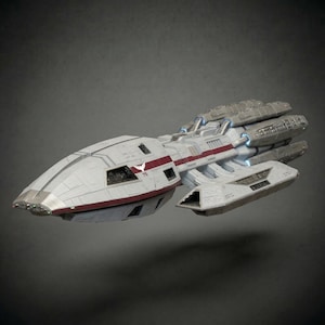 Op de afbeelding: Gedetailleerd model van een ruimteschip, voornamelijk wit met rode en grijze accenten. Het ruimteschip heeft meerdere motoren en een gestroomlijnd ontwerp, wat wijst op een futuristisch thema. Het model staat tegen een neutrale grijze achtergrond.
