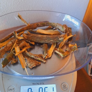 May include: A clear bowl on a digital scale contains dried, tan-colored plant material. The scale reads 0.51 ounces. The date and time, December 20, 2023, 11:14 AM, are displayed on the scale.
