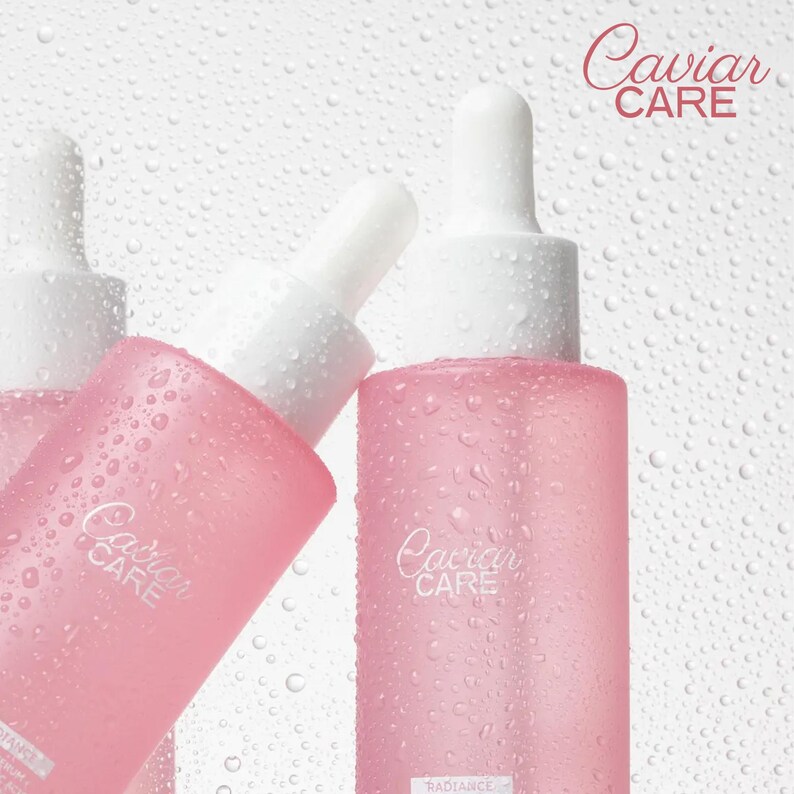 May include: Three pink glass bottles with dropper tops and the text "Caviar Care" on the front. The bottles are wet and have water droplets on them.