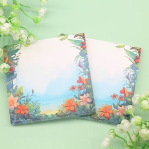 May include: Two floral patterned sticky note pads with a blue and white background. The notes have a border of green leaves and orange flowers.