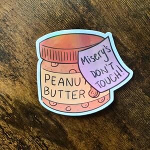 May include: A sticker of a peanut butter jar with a pink and purple note that says "Misery's Don't Touch!"