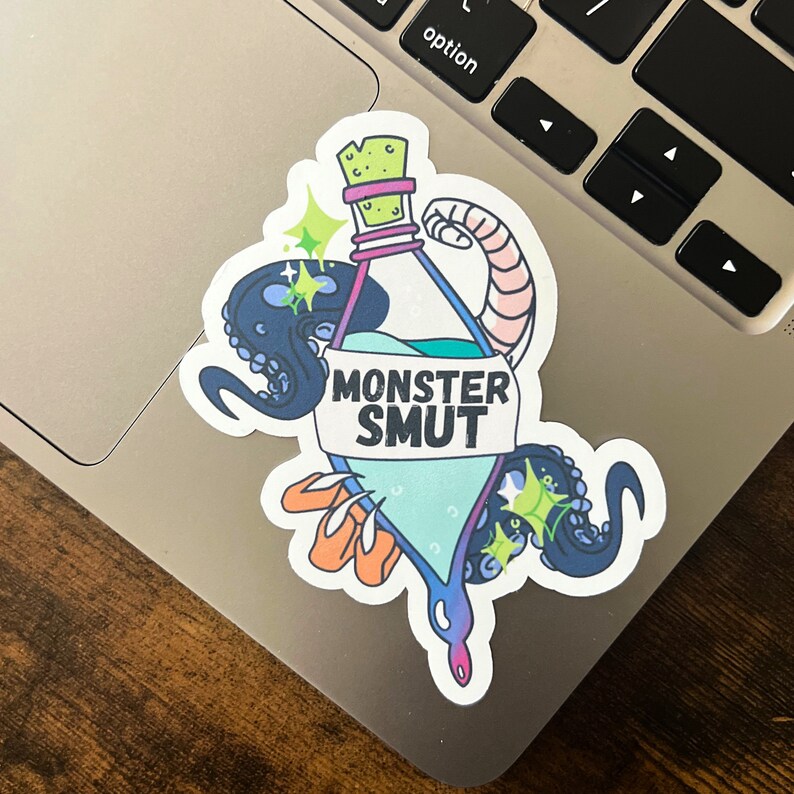 May include: A sticker featuring a blue and green potion bottle with the text "MONSTER SMUT" on a white label. The bottle is surrounded by a pink and blue octopus with green sparkles.