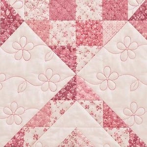 Pode incluir: Uma peça de tecido acolchoado com um design de patchwork em tons de rosa e branco. O padrão inclui blocos geométricos com estampas florais e seções de rosa claro sólido decoradas com contornos costurados de flores e folhas.