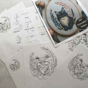K&ouml;nnte beinhalten: Eine Sammlung von Stickmustern mit einem Katzenmotiv. Das Bild zeigt einen fertigen Stickrahmen mit einer Katze sowie mehrere gedruckte Anleitungsbl&auml;tter. Die Bl&auml;tter zeigen das Katzendesign und Sticktechniken. Der Text "PDF Embroidery Pattern" ist sichtbar.