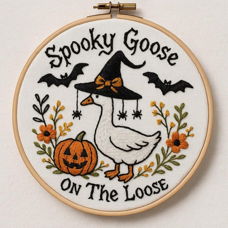 Pu&ograve; includere: Ricamo artistico di Halloween in un telaio di legno. Raffigura un'oca bianca con un cappello da strega, una zucca, pipistrelli e fiori arancioni. Il testo recita "Spooky Goose On The Loose". Il disegno &egrave; ricamato su tessuto bianco.