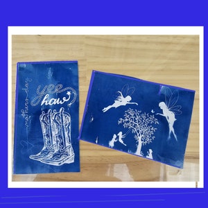 May include: Two cyan blue cards with white designs. One card has a pair of cowboy boots with the text "Yee Haw" and "mother-play". The other card has a tree with fairies and the text "mother-play".