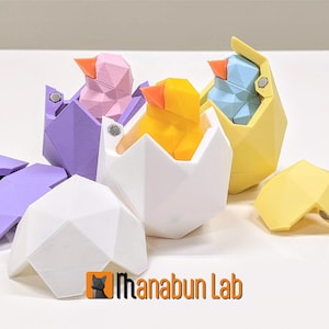 May include: Three geometric bird-shaped puzzles, each with a different color: purple, yellow, and blue. The birds are inside of geometric egg-shaped containers that open and close. The containers are also different colors: purple, yellow, and white.