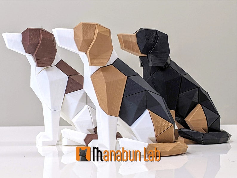 May include: Three geometric dog sculptures in white, brown, black, and tan. The dogs are in a sitting position, with a faceted design. The logo "Manabun Lab" is visible in the bottom left corner. The sculptures are likely made of plastic.
