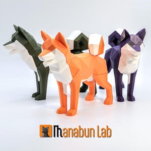 May include: A collection of geometric paper dog sculptures in various colors, including orange, green, and purple. Each dog has a unique polygonal design and stands on a white surface. The logo "Manabun Lab" is visible at the bottom.