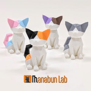 May include: Four geometric cat figurines in various colours, including pink, purple, brown, and grey. The cats are made of white plastic and have a stylised, angular design. The figurines are arranged on a white surface.