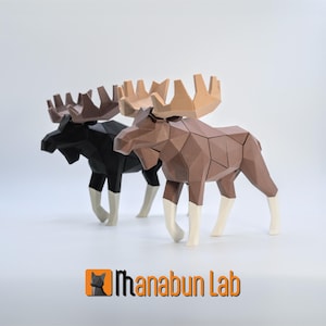 May include: Two geometric paper moose sculptures. One is black, the other is brown. Both have tan antlers and white lower legs. The moose are standing on a white surface. The Manabun Lab logo is in the bottom right corner.