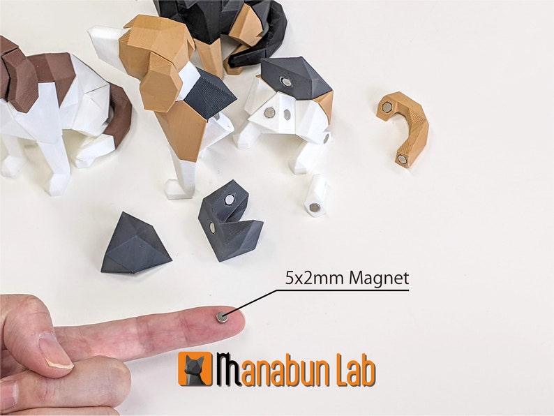 May include: A collection of geometric paper dog models in various stages of assembly, featuring brown, black, and white sections. A 5x2mm magnet is shown, along with the "Manabun Lab" logo.