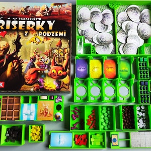 May include: Green plastic organizer with compartments for storing game pieces. The organizer is filled with various colored game pieces, including small cubes, discs, and tokens. The box lid features an illustration of a monster with the text "PRISĚRKY Z PODZEMÍ" in red and black.