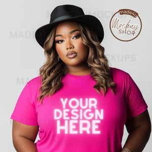 May include: A woman wearing a black fedora and a bright pink t-shirt with the text "YOUR DESIGN HERE" in white.