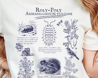 May include: Cream-colored t-shirt featuring a detailed blue illustration of a Roly-Poly, also known as Armadillidium Vulgare, with scientific drawings of insects, plants, and a frog. The text "ROLY-POLY ARMADILLIDIUM VULGARE" is printed at the top.