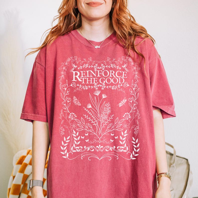 May include: A red t-shirt with a white floral design and the text "Reinforce the Good".