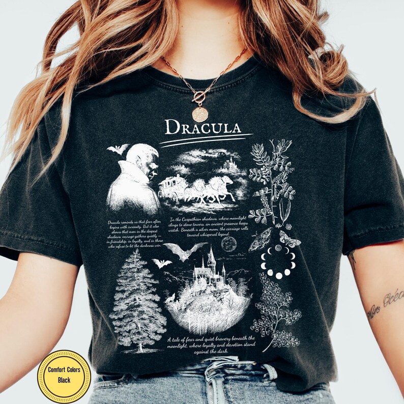 Op de afbeelding: Zwart Comfort Colors T-shirt met een grafisch ontwerp met het woord "Dracula". Het ontwerp bevat illustraties van een kasteel, vleermuizen, een koets en tekst. Het shirt heeft een vintage uitstraling.