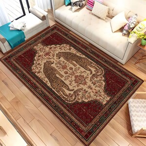 May include: A rectangular rug with a red border and a central design featuring two leopard figures. The rug has a cream-coloured centre with floral patterns and the leopards are in a spotted pattern.