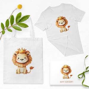 May include: A white tote bag, t-shirt, and greeting card featuring a cartoon lion wearing a gold crown. The lion has a tan mane and tail. The greeting card reads "HAPPY BIRTHDAY!"