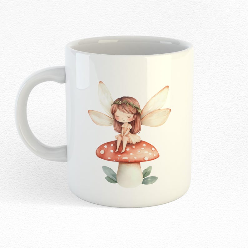Puede incluir: Taza de cer&aacute;mica blanca con una ilustraci&oacute;n de acuarela de un hada sentada en un hongo rojo y blanco. El hada tiene el pelo casta&ntilde;o, un vestido blanco y alas blancas.