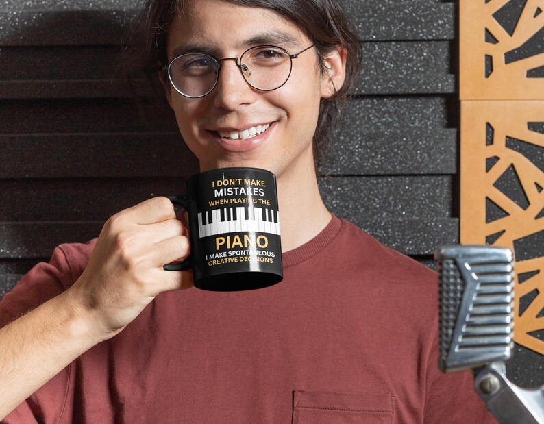 May include: A black coffee mug with white text that reads "I don't make mistakes when playing the piano I make spontaneous creative decisions". The mug has a white image of piano keys.