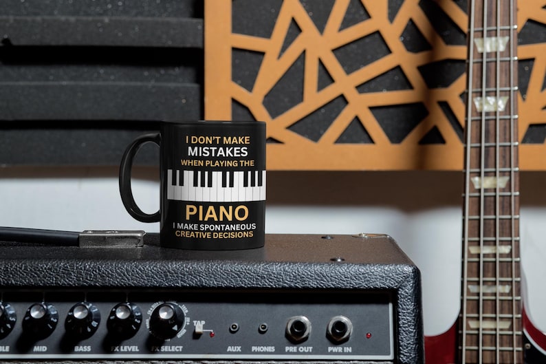 May include: Black coffee mug with a white piano keyboard graphic and the text "I don't make mistakes when playing the piano. I make spontaneous creative decisions."