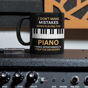 May include: Black coffee mug with a white piano keyboard graphic and the text "I don't make mistakes when playing the piano. I make spontaneous creative decisions."