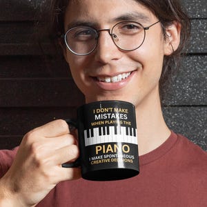 May include: A black coffee mug with a white piano keyboard design and the text "I don't make mistakes when playing the piano. I make spontaneous creative decisions."