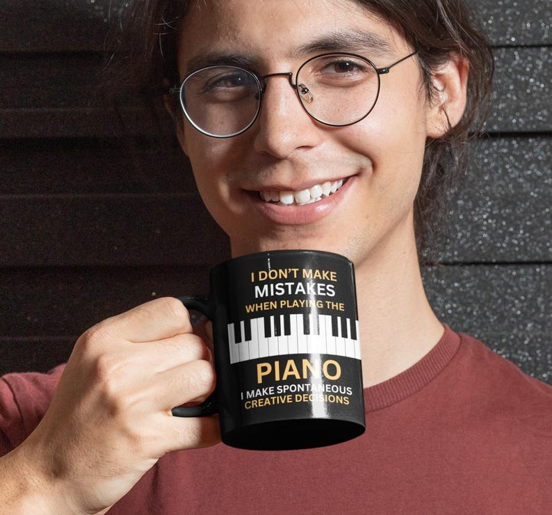 May include: A black coffee mug with a white piano keyboard design and the text "I don't make mistakes when playing the piano. I make spontaneous creative decisions."