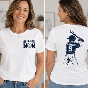 Könnte beinhalten: Ein weißes Kurzarm-T-Shirt mit einer dunkelblauen Grafik auf der linken Brust, die BASEBALL MOM mit einem herzförmigen Baseball zeigt. Die Rückseite zeigt eine dunkelblaue Grafik eines Baseballspielers mit dem Namen JAMES und der Nummer 9.