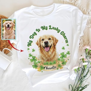 May include: White t-shirt featuring a Golden Retriever illustration with the text "My Dog Is My Lucky Charm." The design includes green shamrocks and a banner with the name "Charlie." A smaller photo of the dog is on the left.