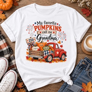 May include: A white t-shirt featuring a graphic of a red pickup truck carrying pumpkins. The text reads My favorite PUMPKINS call me Grandma. The truck bed includes a sign labeled 250, a plaid blanket, and pumpkins labeled Sophia, Lucy, and Jack.
