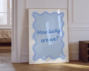 May include: A framed print with a blue and white wavy border. The text inside the border reads "How lucky are we?"