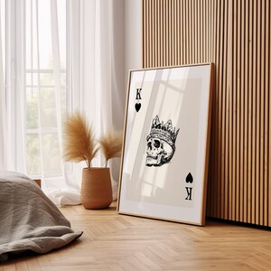 May include: A framed print of a playing card with a skull wearing a crown. The card is the King of Hearts.