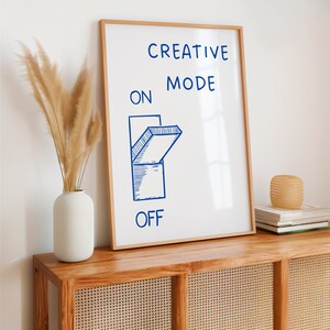 Może przedstawiać: Wydruk w ramie z białym tłem i niebieskim tekstem, kt&oacute;ry brzmi "CREATIVE MODE ON OFF". Słowo "ON" jest wyr&oacute;żnione niebieską ilustracją przełącznika w pozycji "włączony".