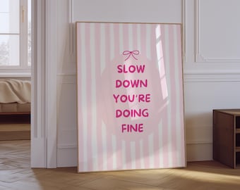 May include: Pink and white striped poster with a pink circle in the center. The circle has a pink bow at the top and the text "SLOW DOWN YOU'RE DOING FINE" in pink.