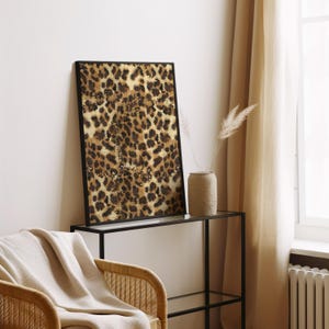 May include: A framed print of a leopard print pattern in shades of brown, gold, and black. The print is hanging on a wall above a black metal shelf.